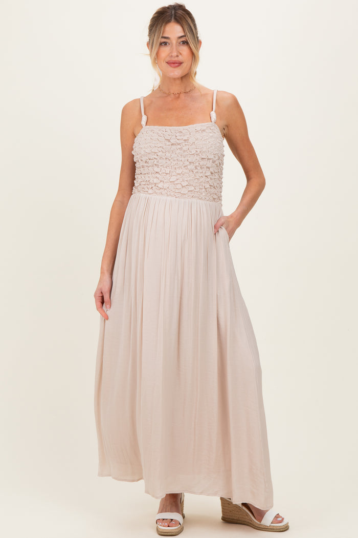 woman wearing a light beige maternity maxi dress with a textured bodice and pockets