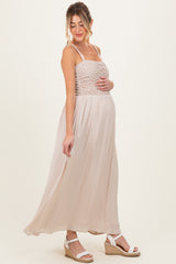 woman wearing a light pink maternity maxi dress with a ruffled bodice and holding her baby bump
