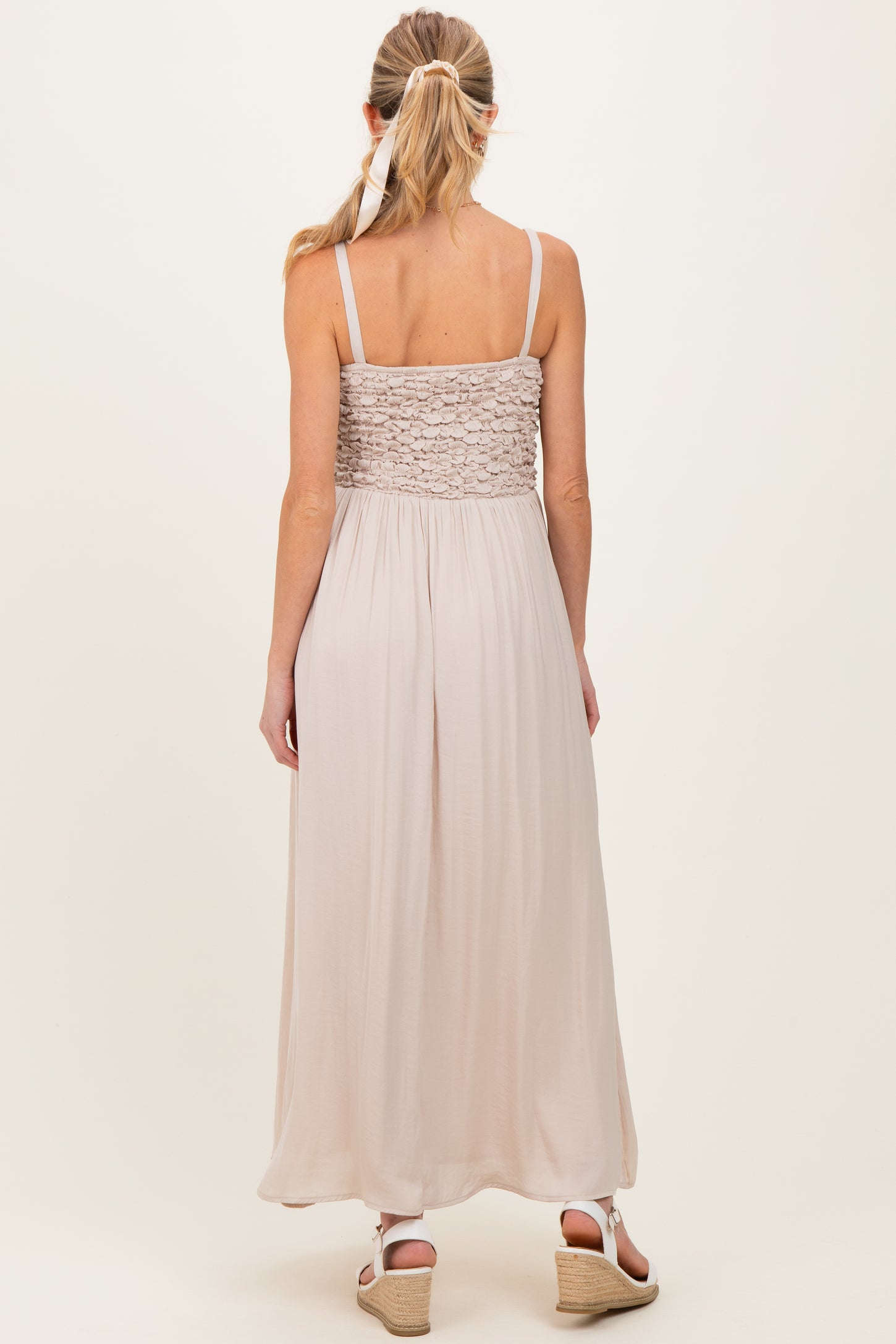 woman wearing a beige maternity maxi dress with a lace bodice, showing the back view