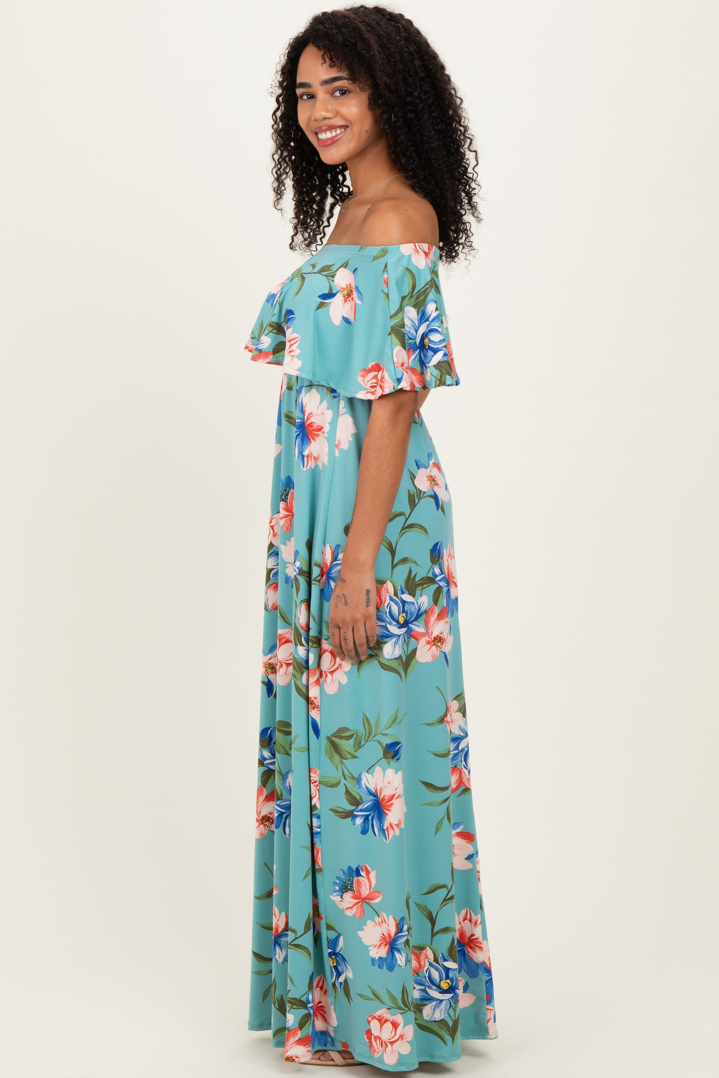 woman wearing a teal off-the-shoulder floral maxi dress with ruffled sleeves and a fitted bodice