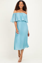 woman wearing a light blue off-the-shoulder pleated dress with ruffle detailing and flowing sleeves