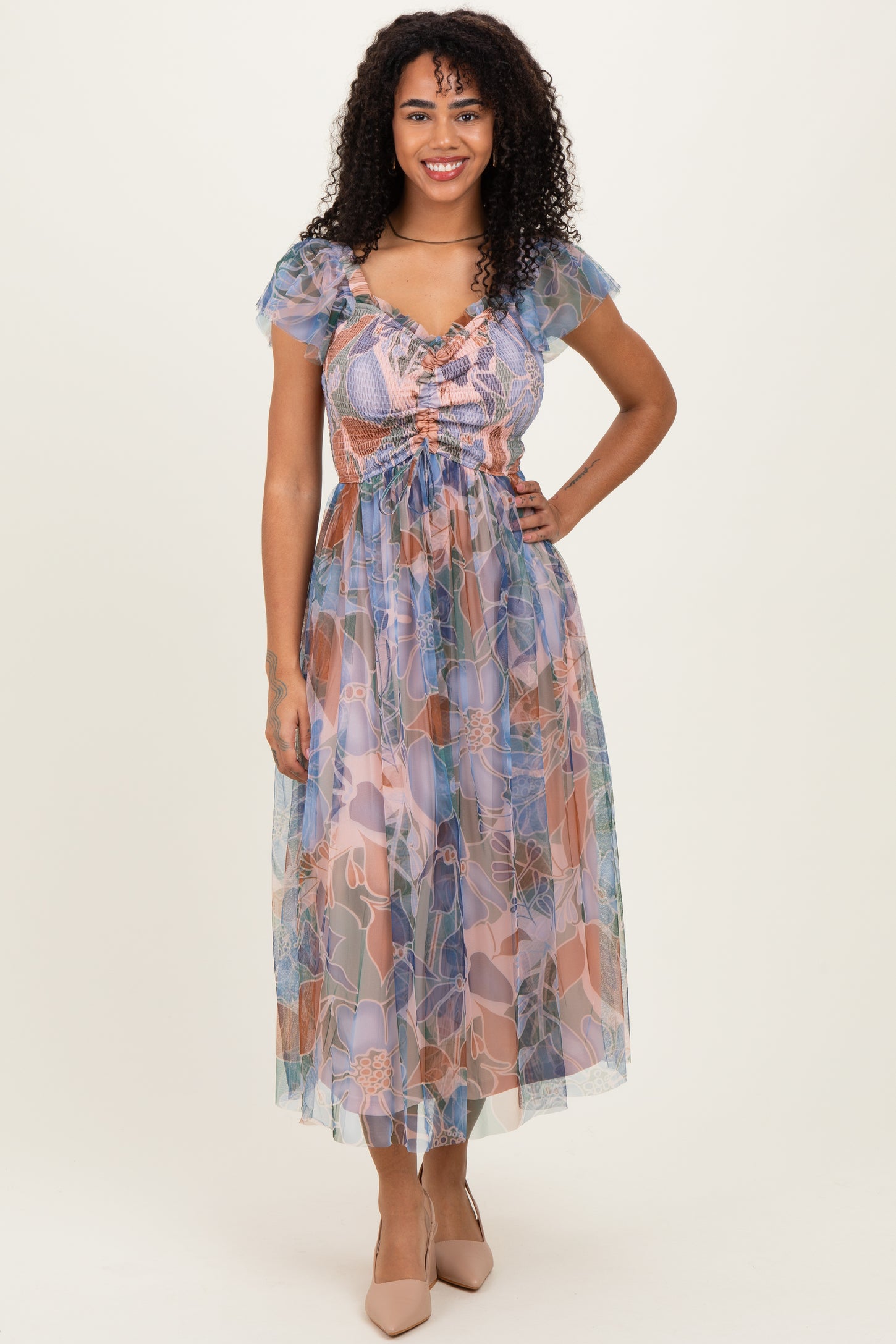 woman wearing a floral sheer maxi dress with puff sleeves and a cinched waist in pastel colors.