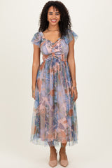 woman wearing a floral print maxi dress with ruffled sleeves and a cinched waist, standing against a neutral background