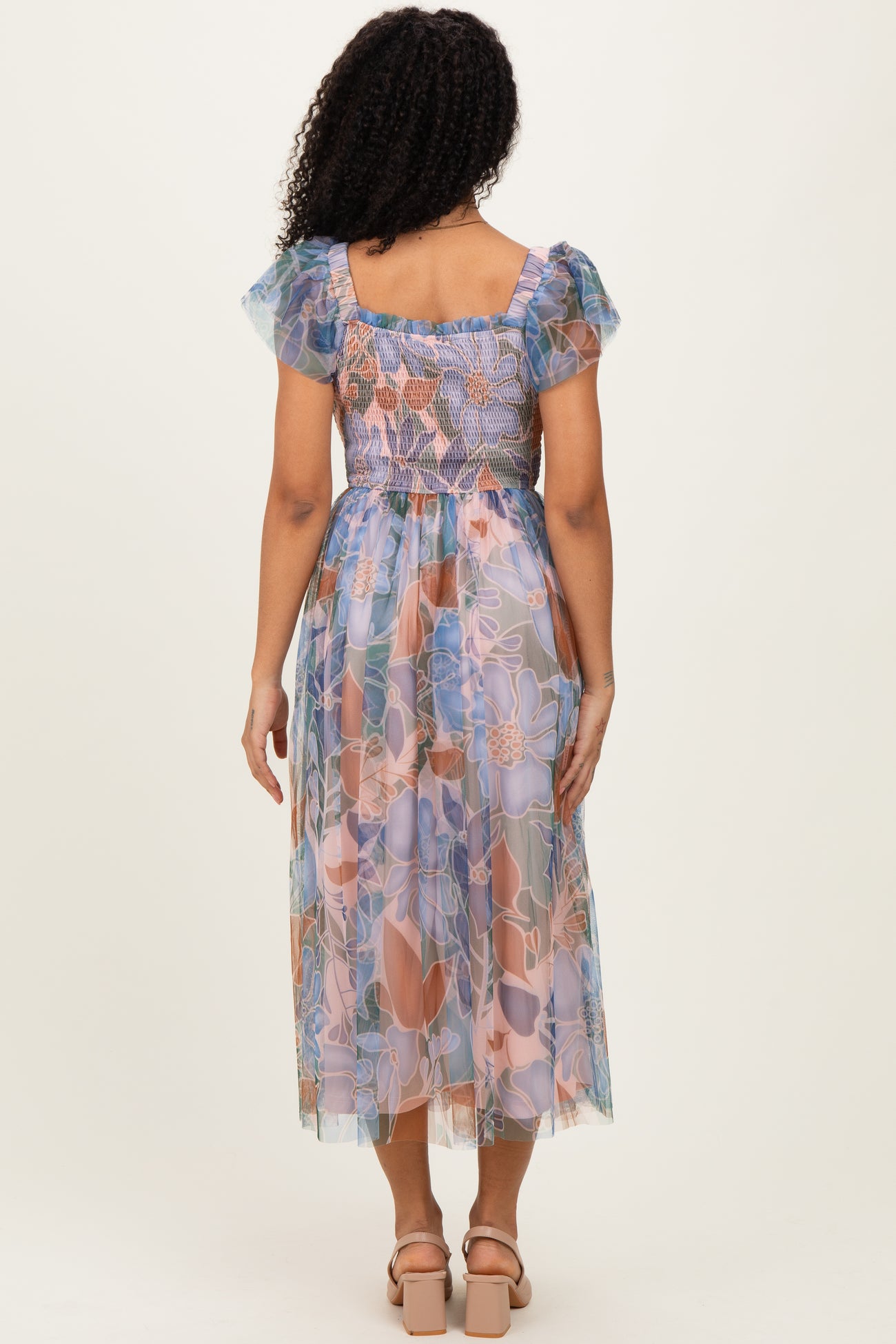 woman wearing a floral printed midi dress with puff sleeves and a smocked bodice, viewed from the back