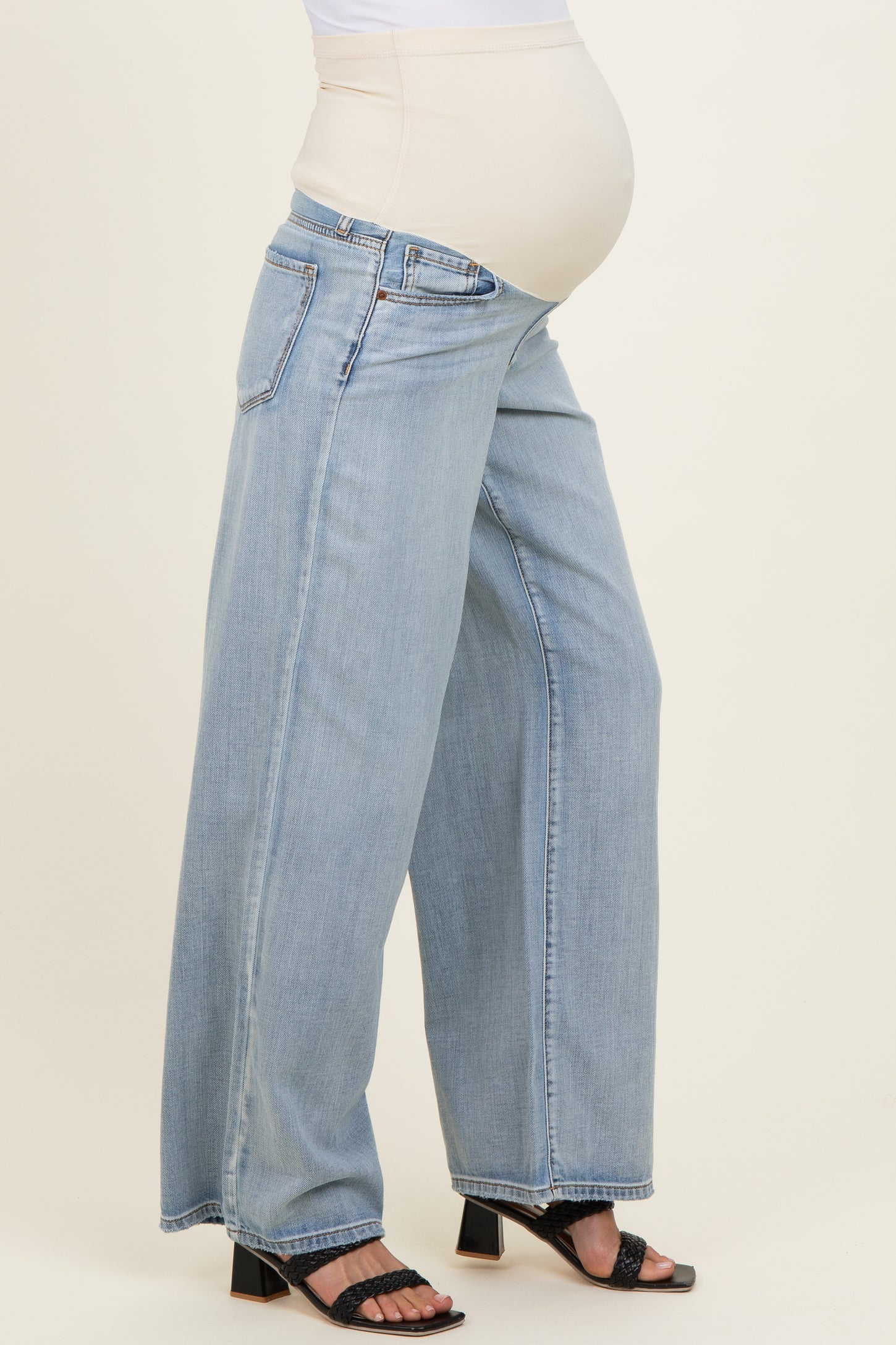 woman wearing light blue wide-leg maternity jeans with a stretchy beige waistband and visible baby bump