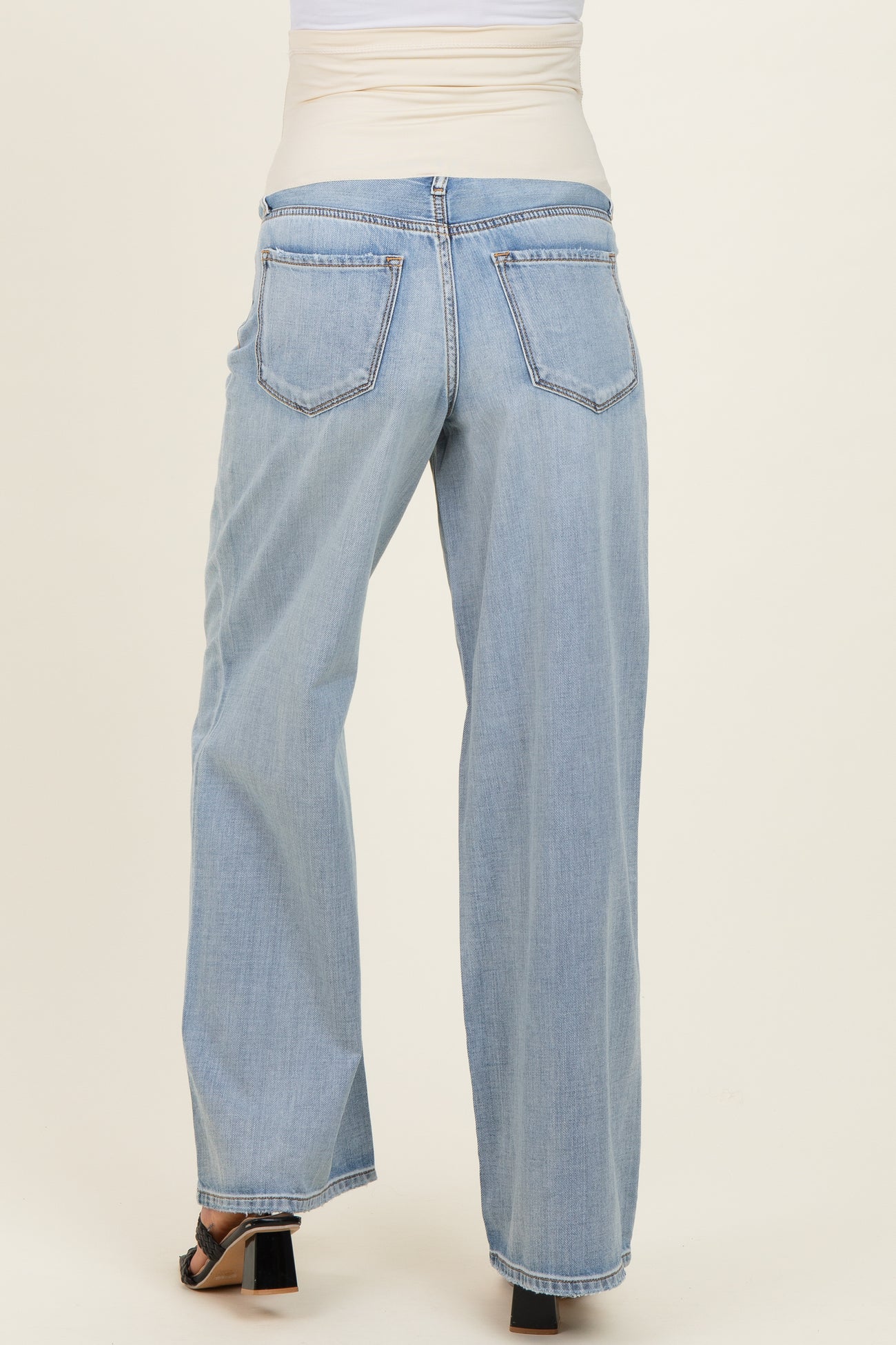 woman wearing light wash maternity jeans with a wide-leg style and an elastic pregnancy-friendly waistband