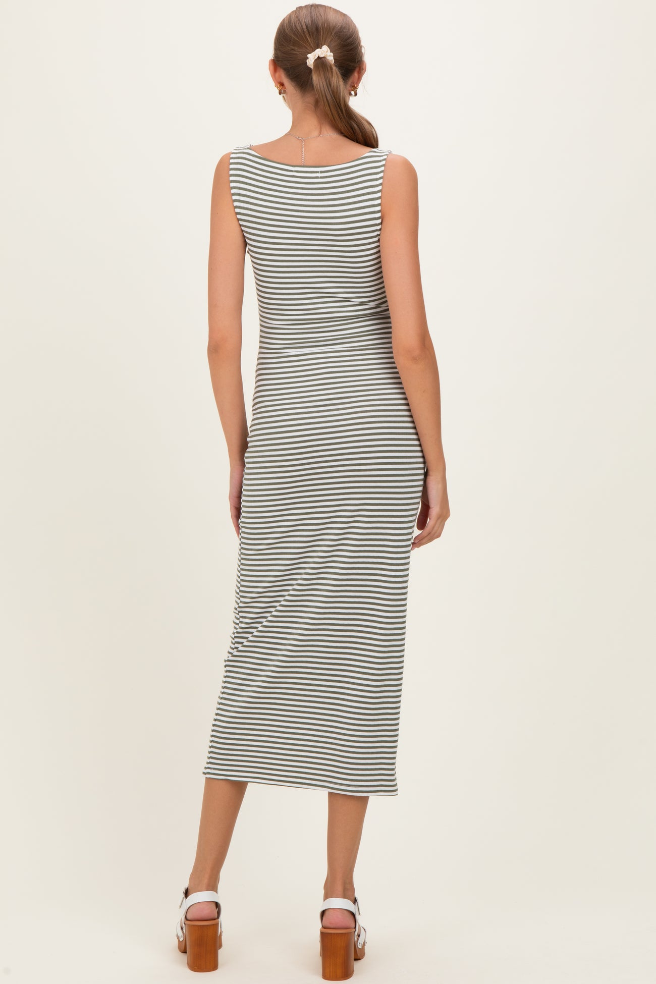 woman wearing a gray and white striped maternity dress, showing a fitted style and knee-length hem