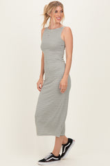 woman wearing a gray and white striped sleeveless midi dress with a fitted silhouette and black sneakers