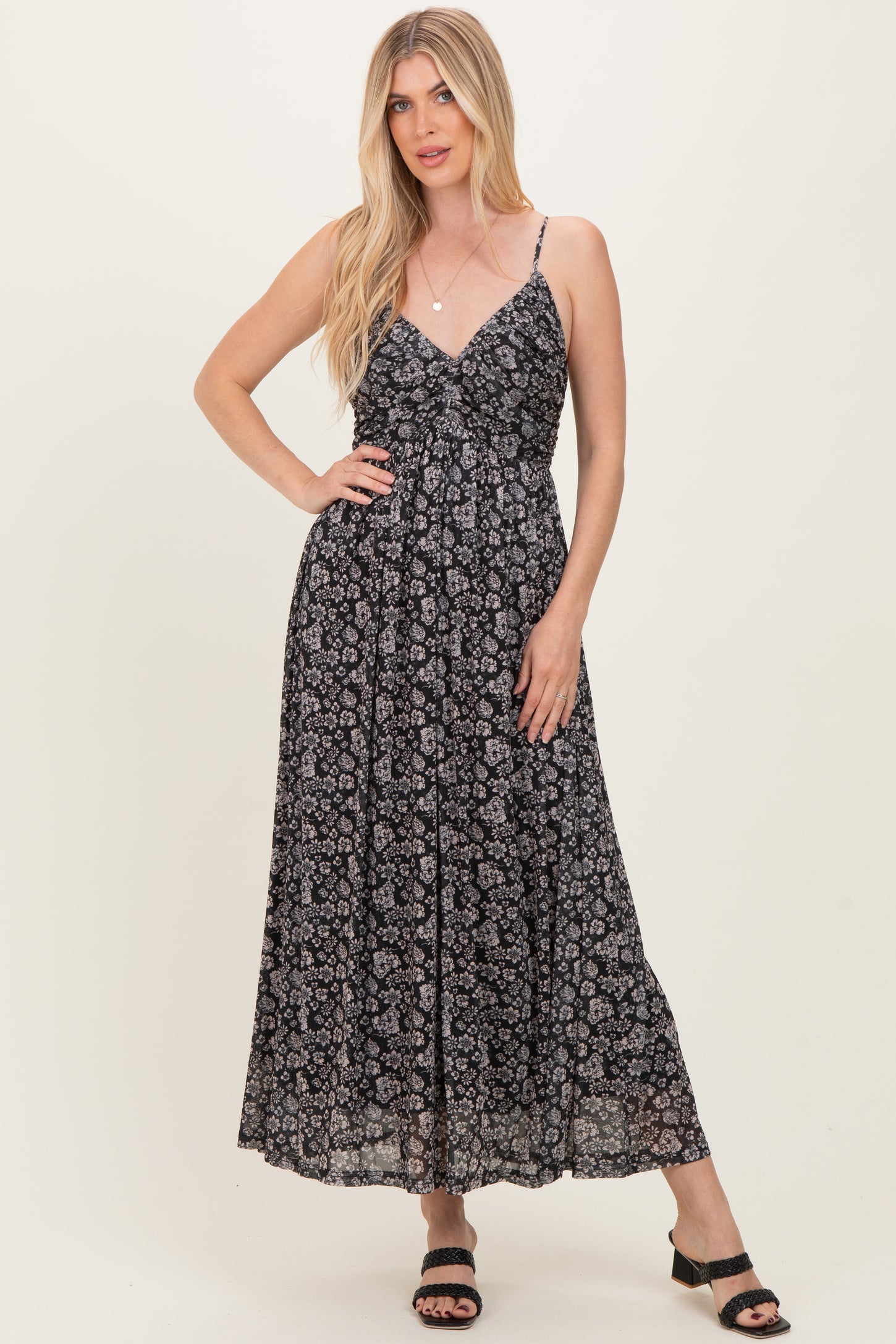 woman wearing a black floral maxi dress with spaghetti straps and a fitted bodice