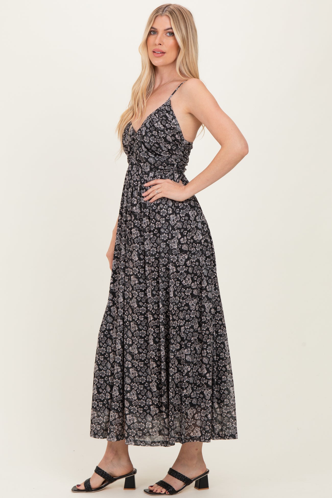 woman wearing a black floral maxi dress with spaghetti straps and a fitted bodice