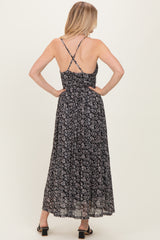 woman wearing a black floral maxi dress with a ruched back and crisscross straps, shown from the back