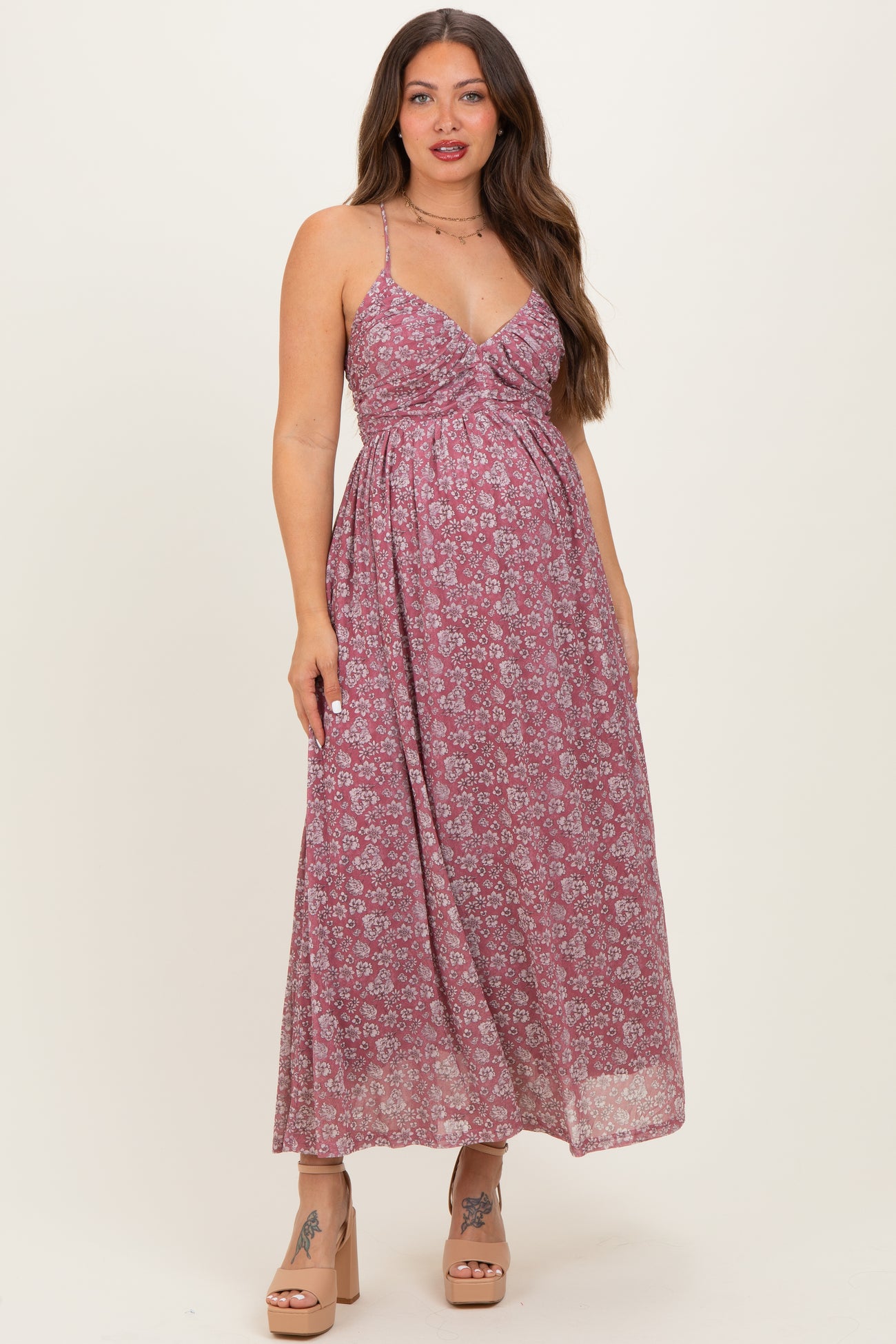 woman wearing a floral print maternity maxi dress with adjustable straps and a cinched waist, baby bump visible