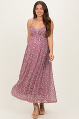 woman wearing a floral pink maternity maxi dress with a fitted bodice and flowing skirt, showing her baby bump