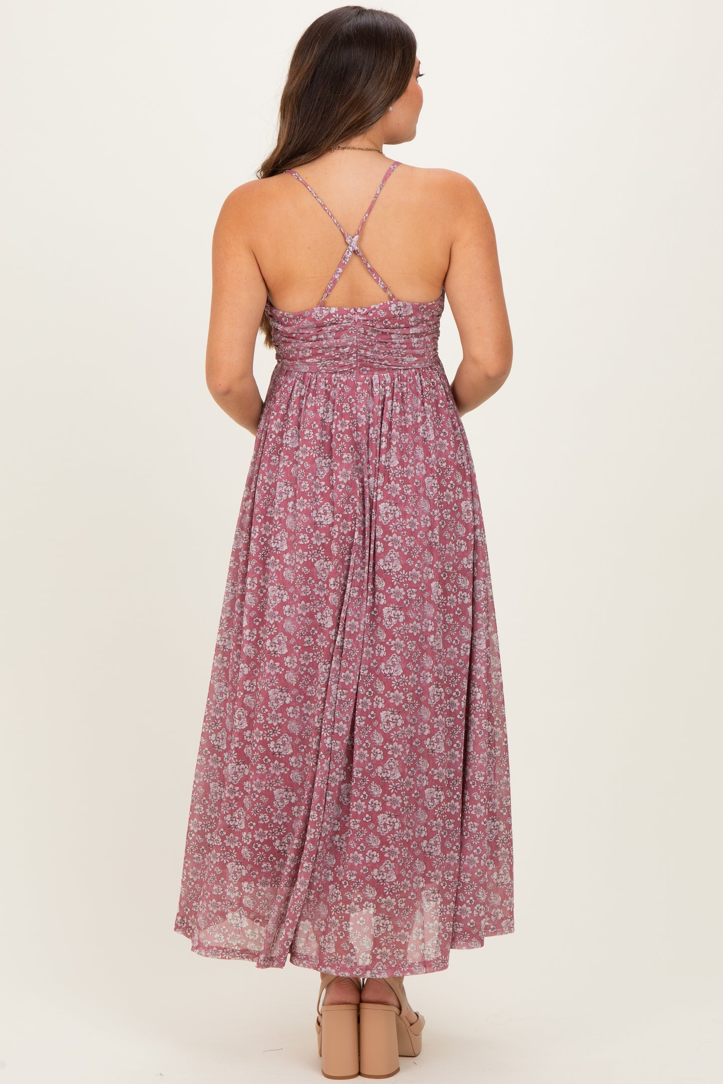 woman wearing a floral print maternity maxi dress with crisscross straps and flowing back design