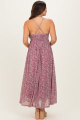 woman wearing a floral print maternity maxi dress with crisscross straps and flowing back design