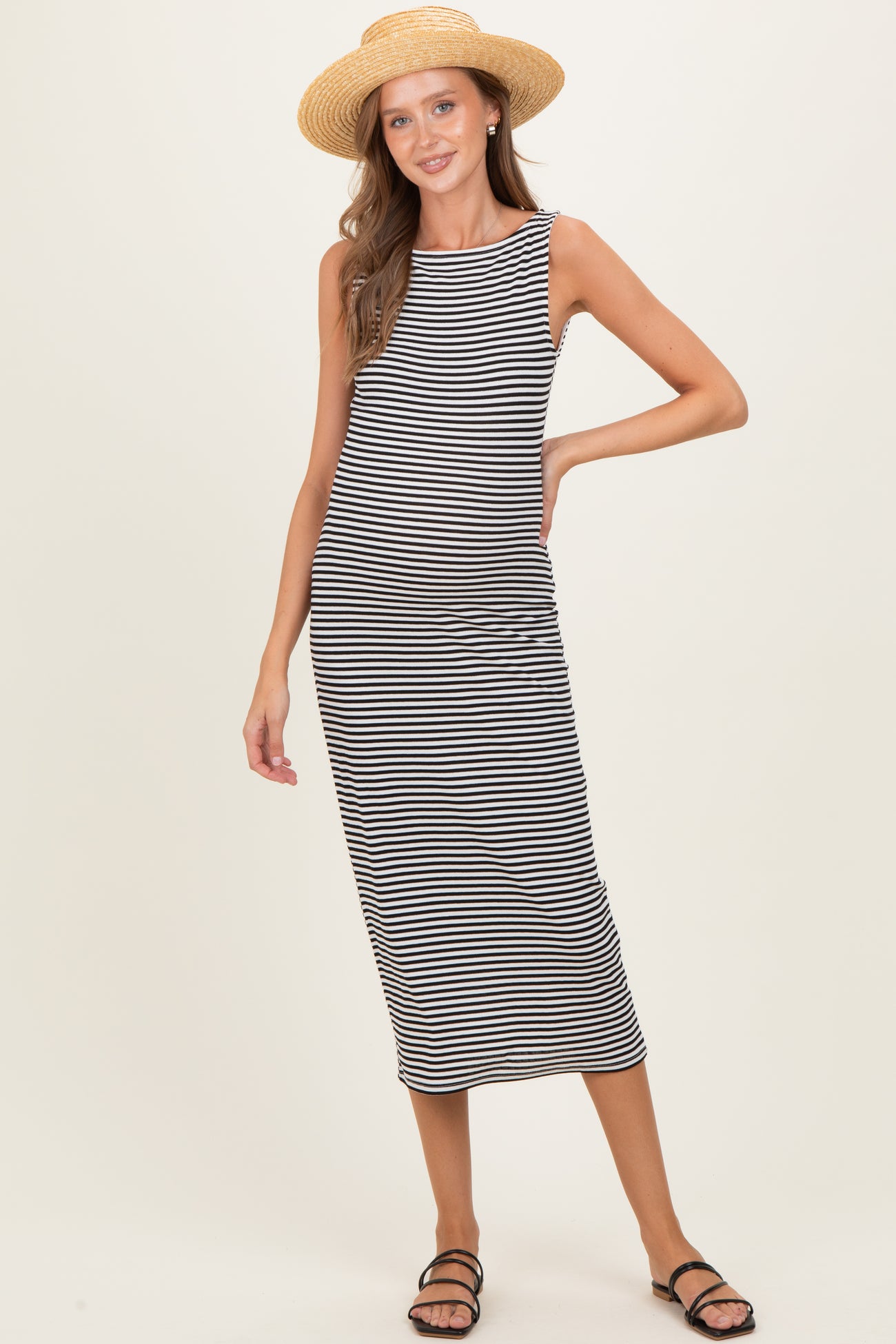 woman wearing a black and white striped maternity dress with a relaxed fit and a straw hat