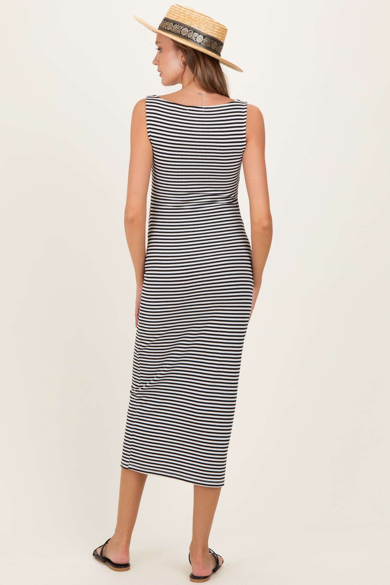 woman wearing a black and white striped maternity maxi dress, standing with her back facing the camera