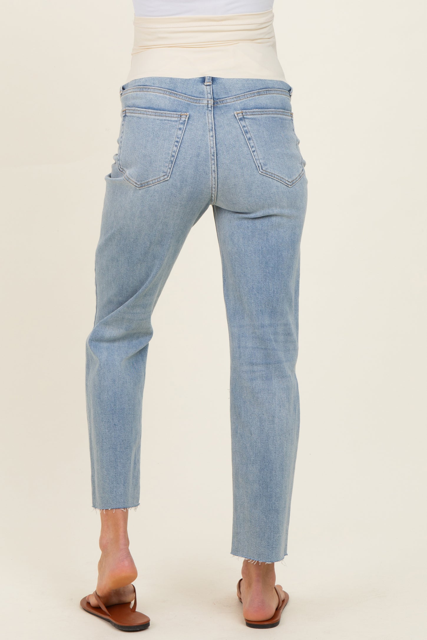 maternity wear light blue skinny jeans with a frayed hem, model seen from the back