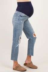 woman wearing distressed light blue maternity jeans with a navy blue over-the-belly panel and a visible baby bump