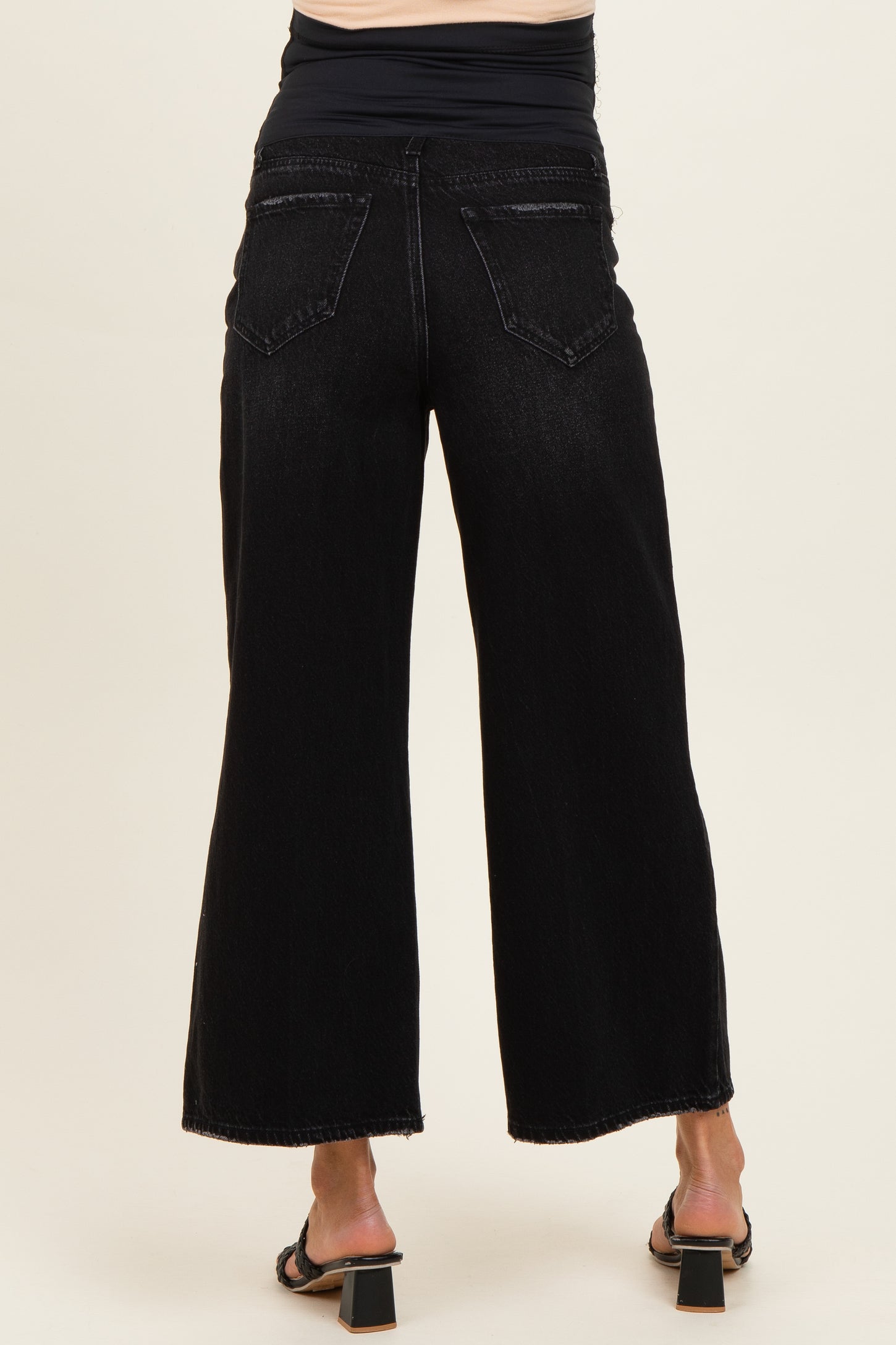 woman wearing black wide leg maternity jeans, showing the back view, with a fitted black top