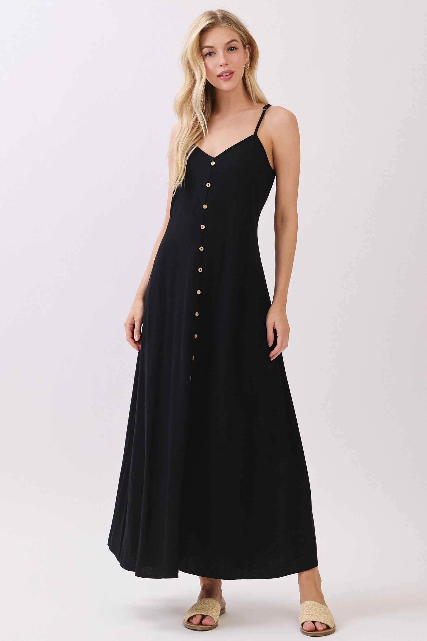 woman wearing a black spaghetti strap maxi dress with button details and a flowy silhouette