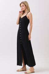 woman wearing a black maxi dress with buttons down the front and thin straps, styled with flat sandals
