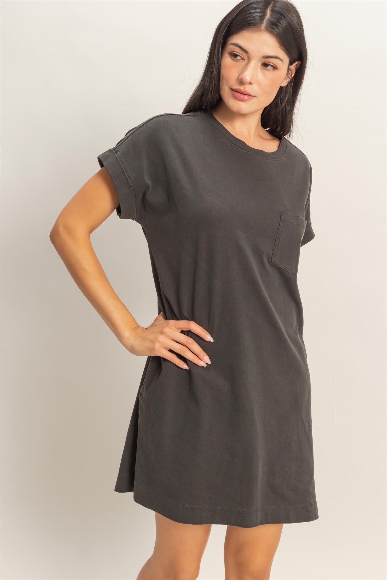 woman wearing a dark gray oversized t-shirt dress with a single chest pocket and rolled short sleeves