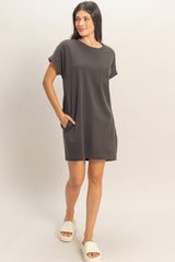 woman wearing a dark gray short sleeve t-shirt dress with a pocket and side seam pockets, standing with one foot forward