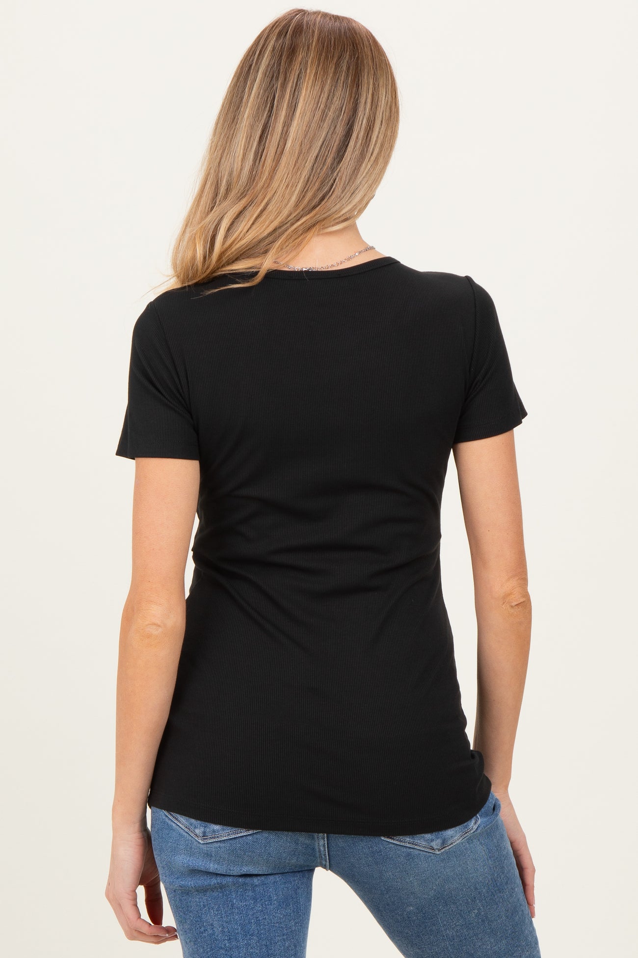 woman wearing a black short sleeve maternity top, viewed from the back with a slim fit silhouette