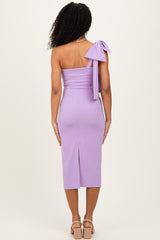 woman wearing a lavender one-shoulder dress with a bow detail on the shoulder and a slit at the back