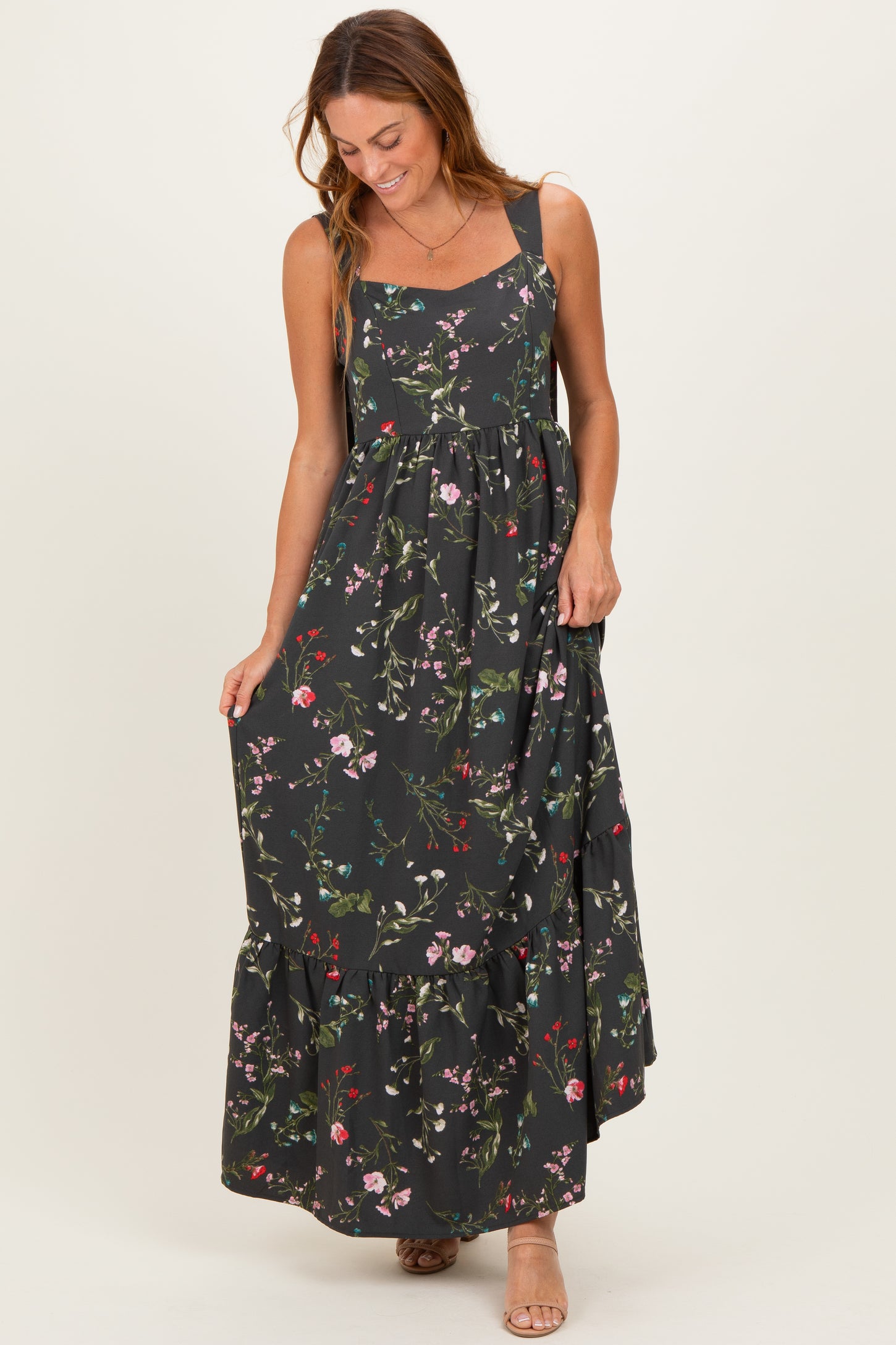 woman wearing a black floral maxi dress with a square neckline and ruffle hem