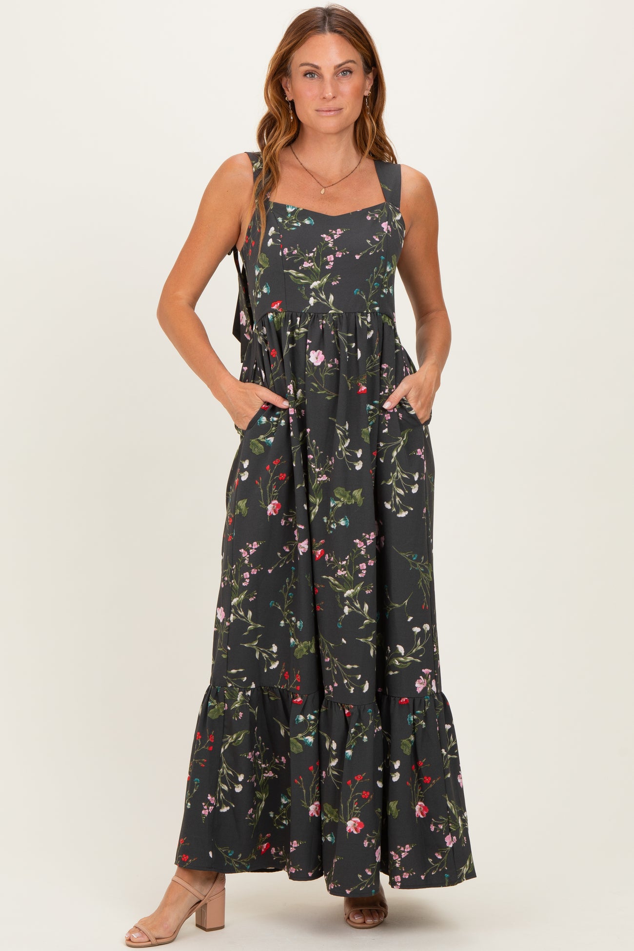 woman wearing a black floral maxi dress with pockets and ruffled hem
