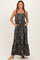 woman wearing a black floral maxi dress with pockets and ruffled hem