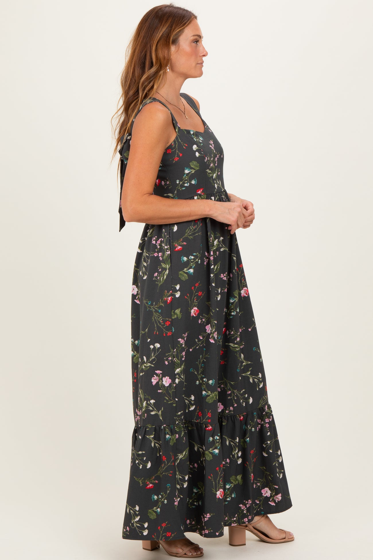 woman wearing a black floral maxi dress with a ruffled hem and tie straps