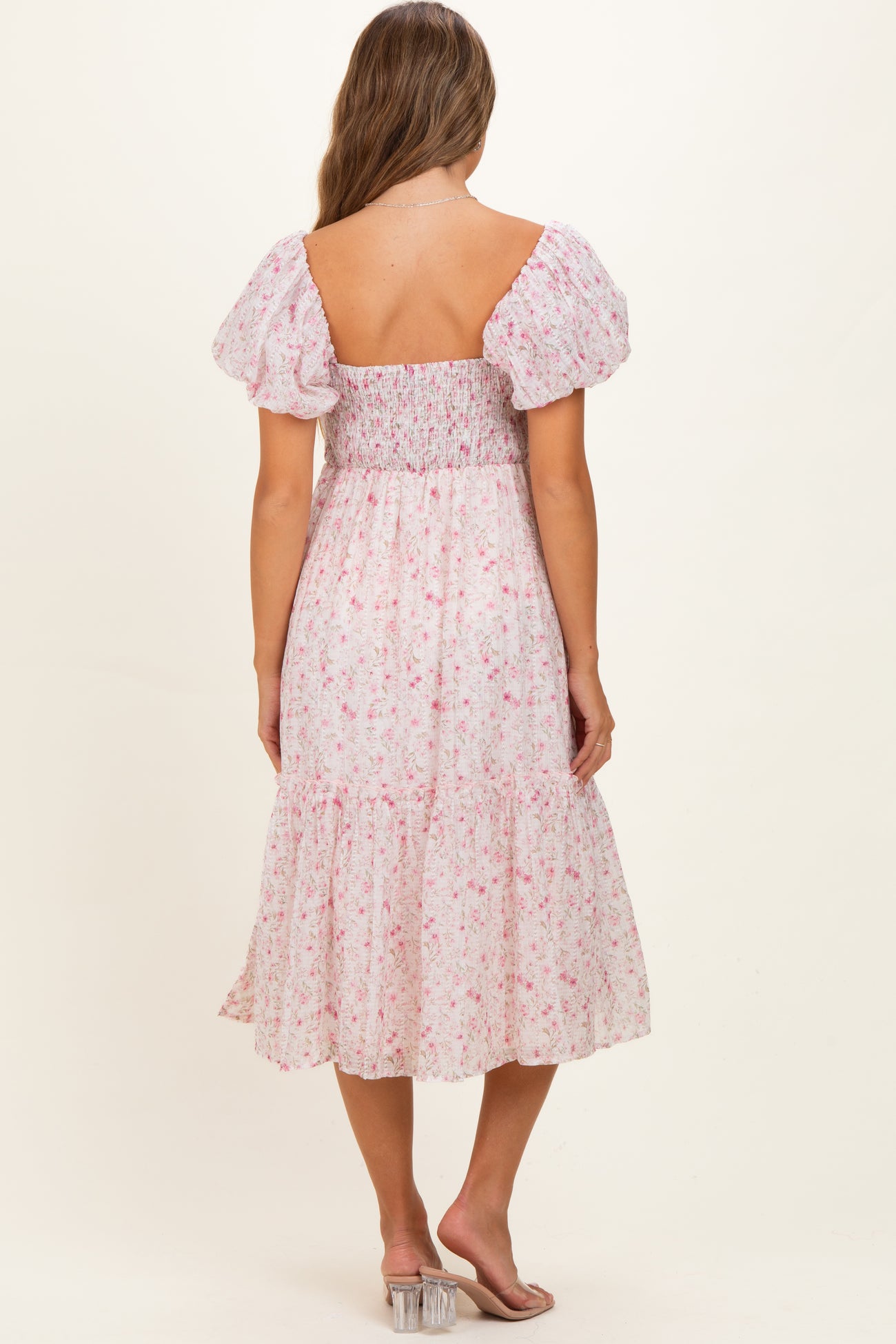 woman wearing a floral maternity dress with puff sleeves and a smocked bodice, showing a baby bump from the back