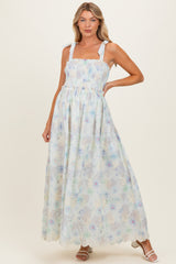 woman wearing a light blue floral maternity maxi dress with smocked bodice and tie straps