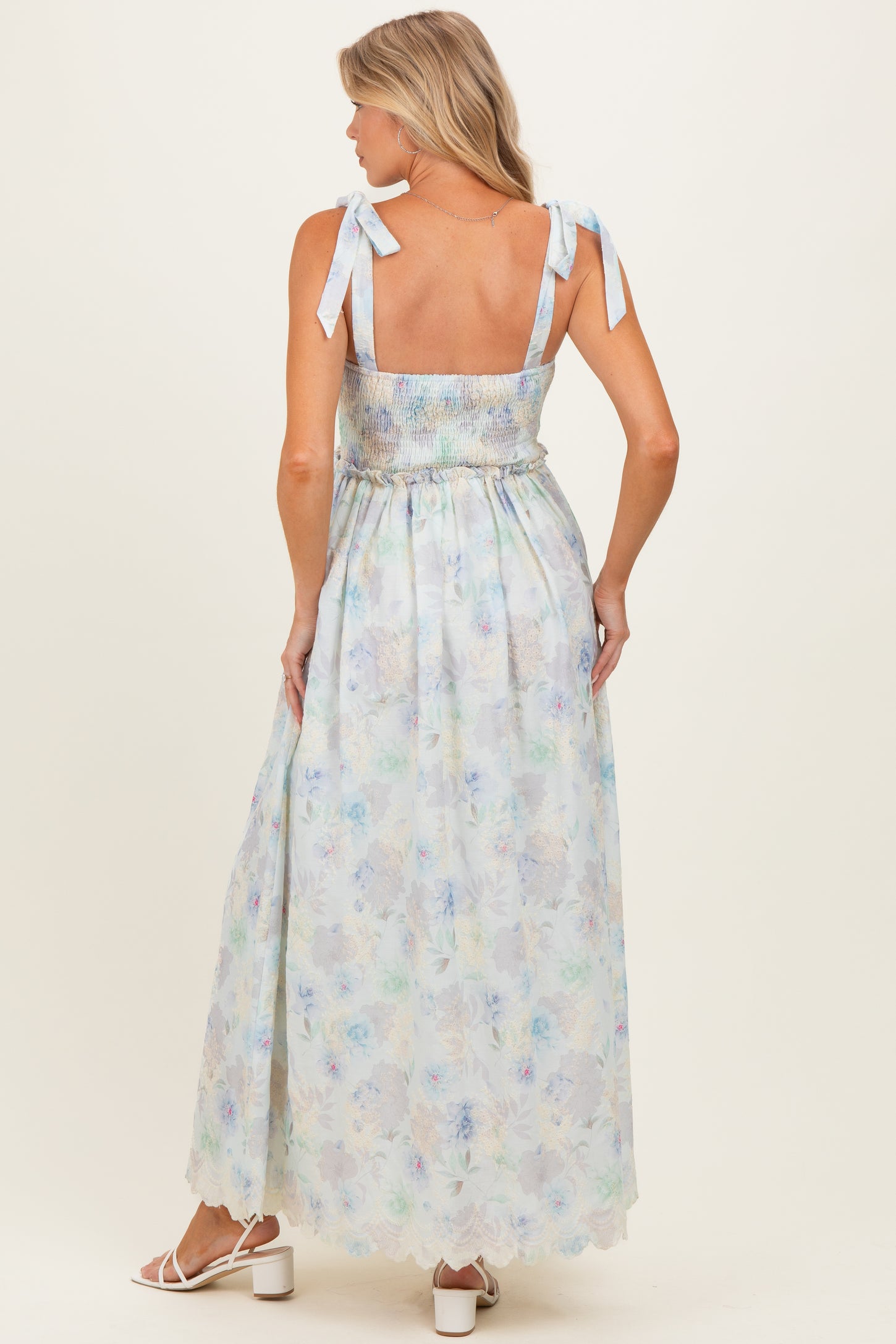 woman wearing a floral print maternity maxi dress with tie straps and a smocked bodice, showing her back