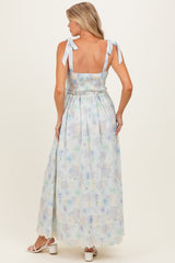 woman wearing a floral print maternity maxi dress with tie straps and a smocked bodice, showing her back