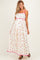 woman wearing a floral maternity maxi dress with pink trim and spaghetti straps, showcasing her baby bump