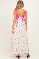 woman wearing a floral print maternity maxi dress with pink accents and a tied back detail