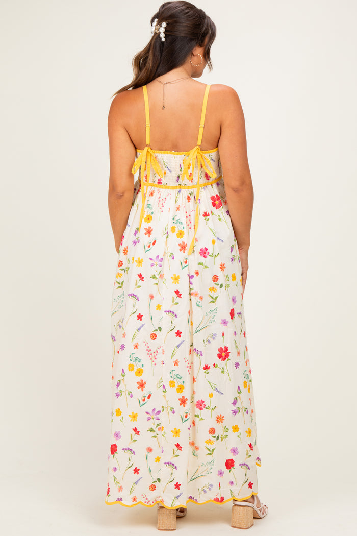 woman wearing a floral print maternity maxi dress with spaghetti straps and adjustable ties at the back