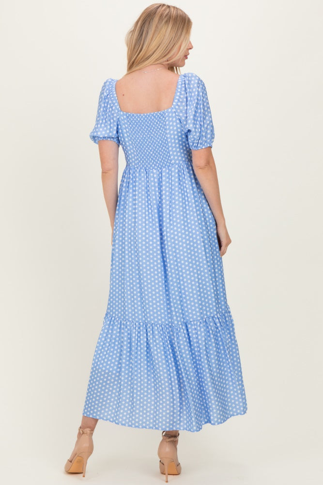 woman wearing a blue polka dot maxi dress with short puff sleeves and a tiered hem