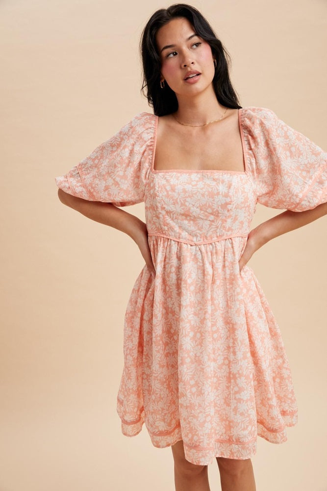 woman wearing a pink floral puff sleeve dress with a square neckline and a cinched waist