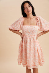 woman wearing a pink floral puff sleeve dress with a square neckline and a cinched waist