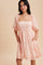 woman wearing a light pink floral square neckline dress with short puff sleeves and pockets