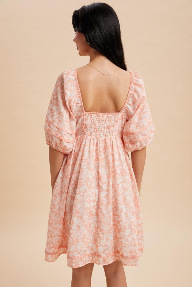 woman wearing a pink and white floral short dress with puff sleeves and a smocked back detail