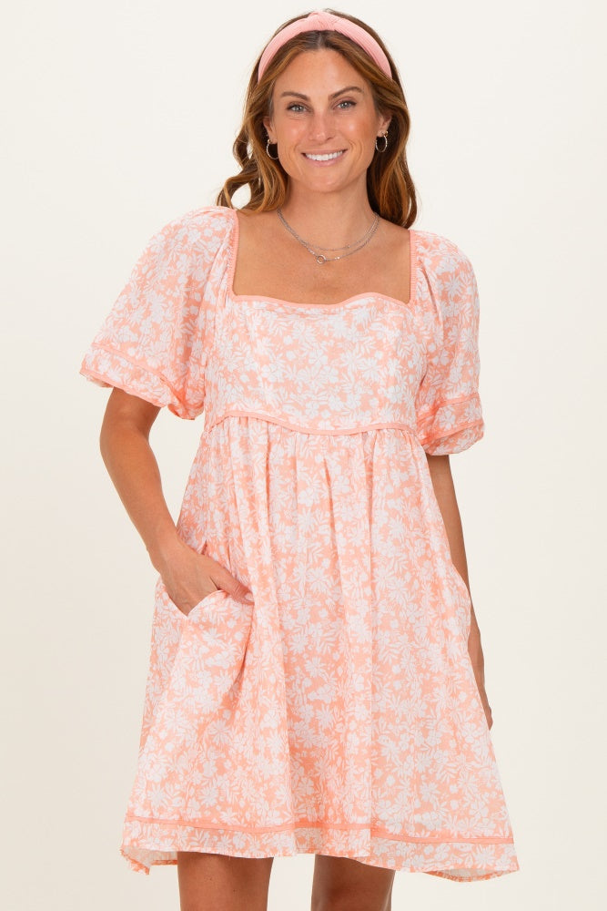 woman wearing a pink floral short sleeve dress with a square neckline and pockets