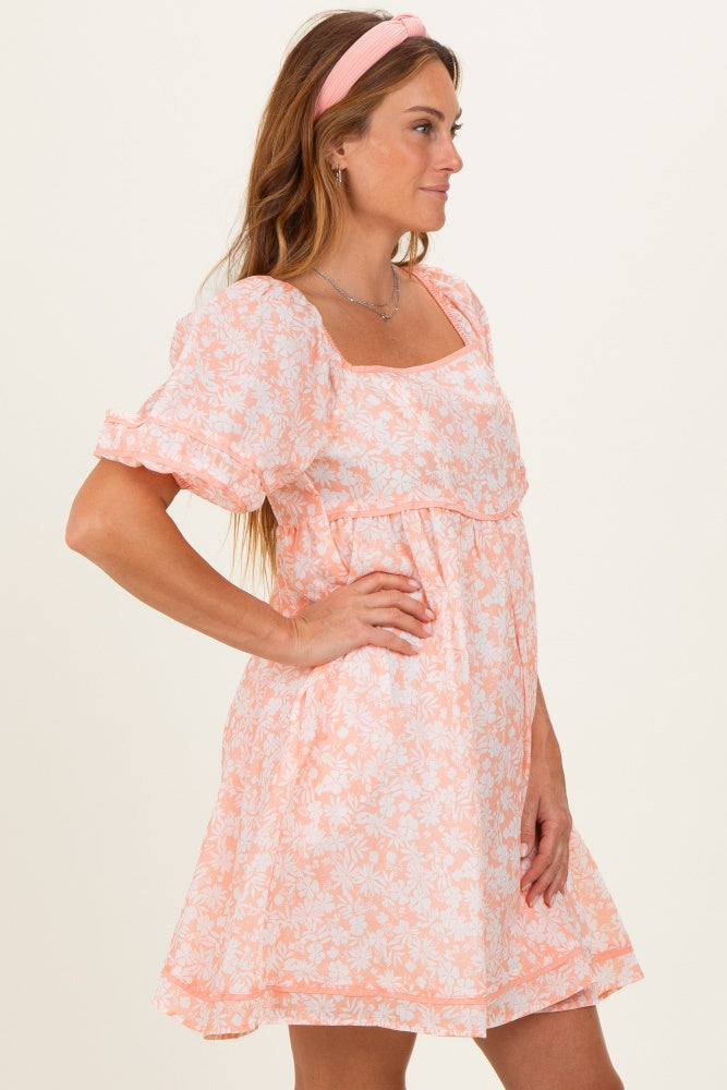 woman wearing a short pink floral dress with puff sleeves and a square neckline, styled with a headband