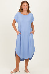 woman wearing a light blue short sleeve midi dress with side pockets and a curved hem