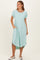 woman wearing a mint green ribbed midi dress with short sleeves and pockets, standing against a light background
